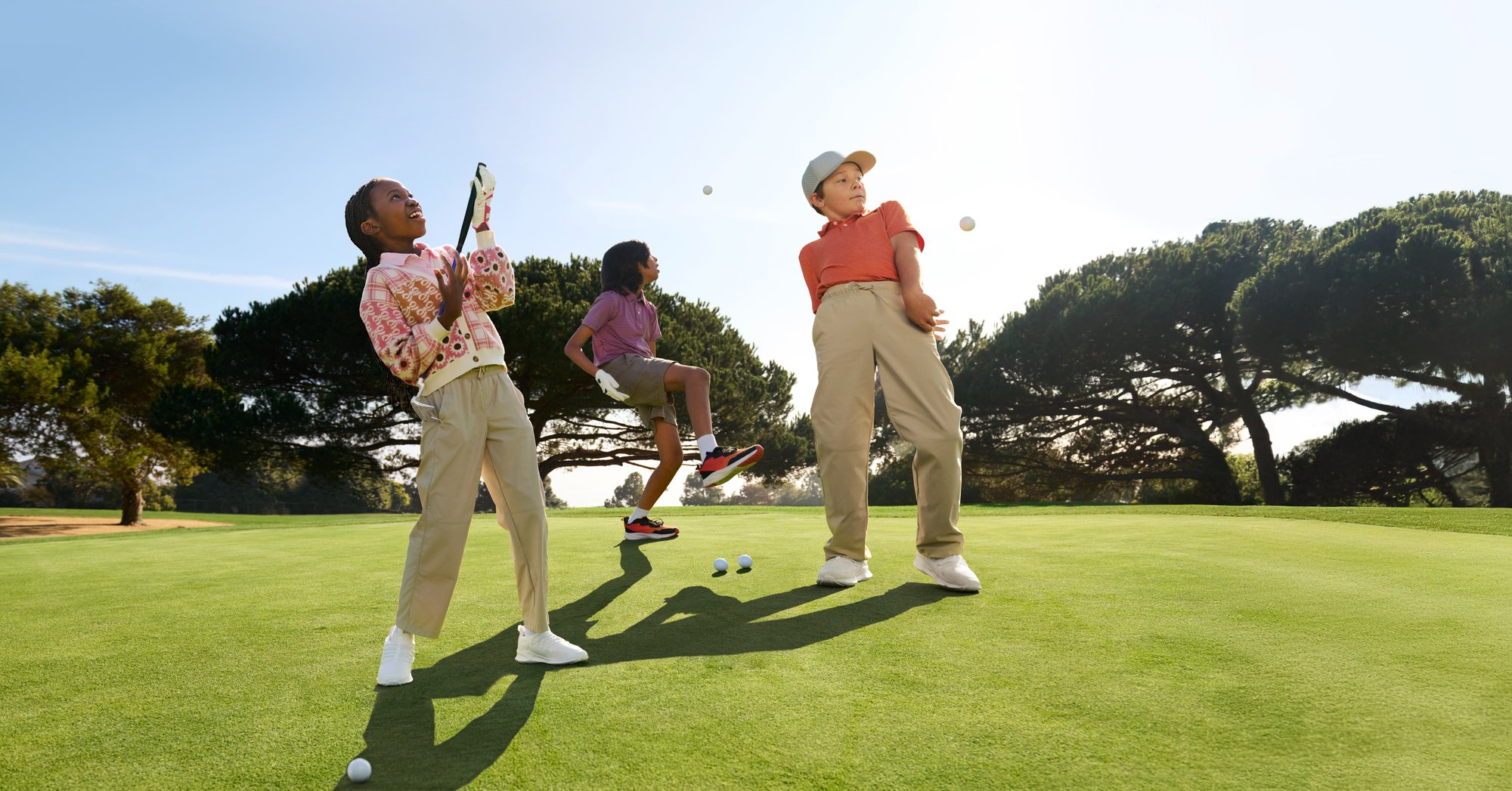 Three youth golfers joyfully play around on a beautifully maintained course